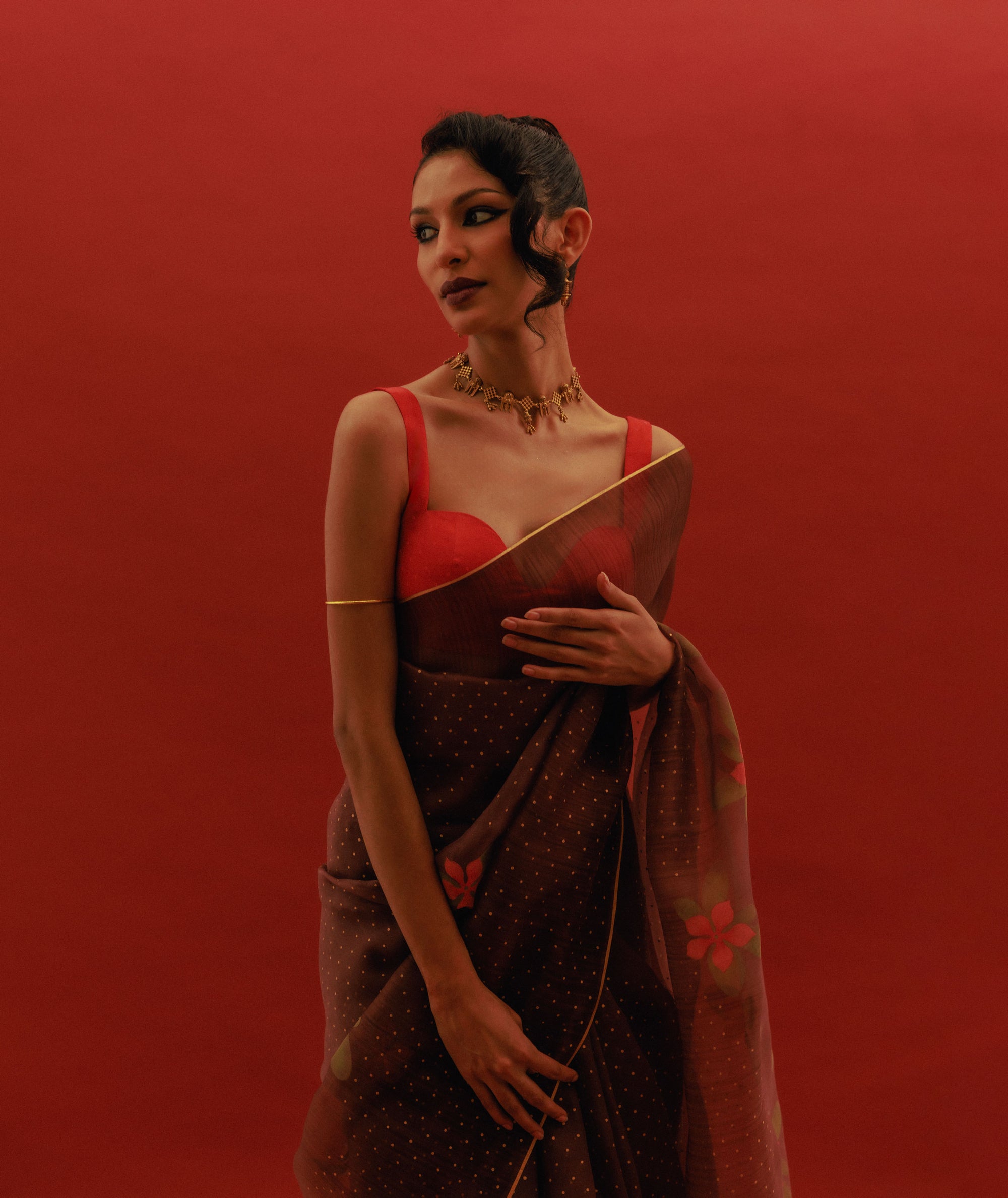 Woman wearing a brown organza saree with peach blouse